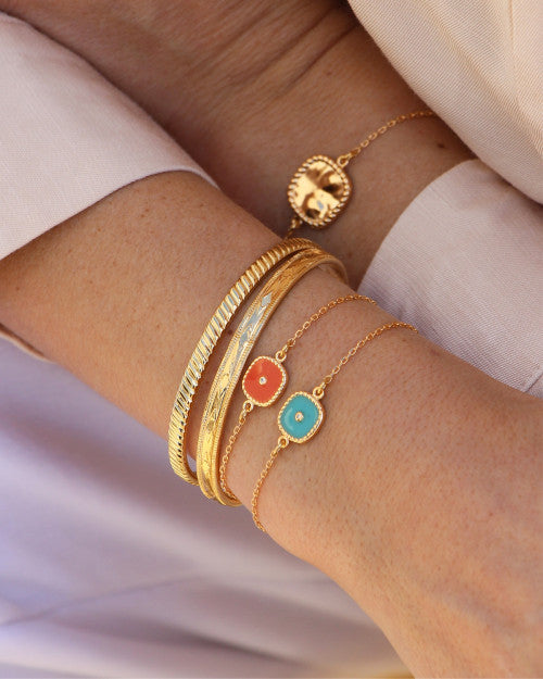 femme portant des joncs plaqué or de chez nilai et des bracelets belize orange et turquoise
