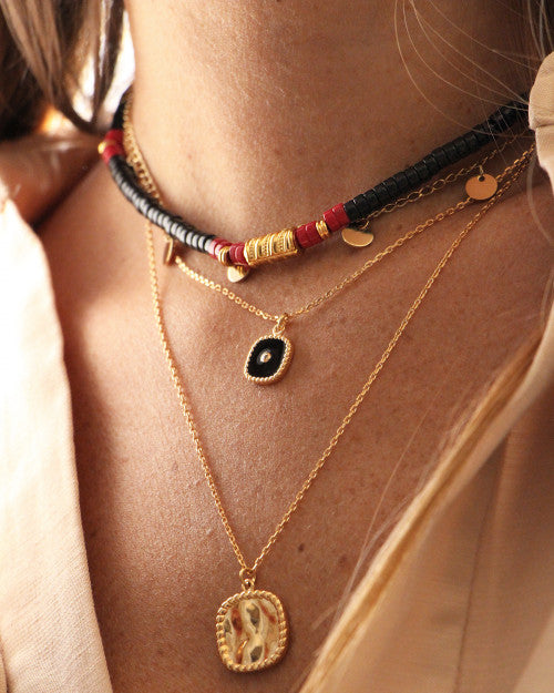 femme portant le collier surfer nilai composé de pierres howlites noires. Elle porte aussi le collier sally et le collier bélize noir