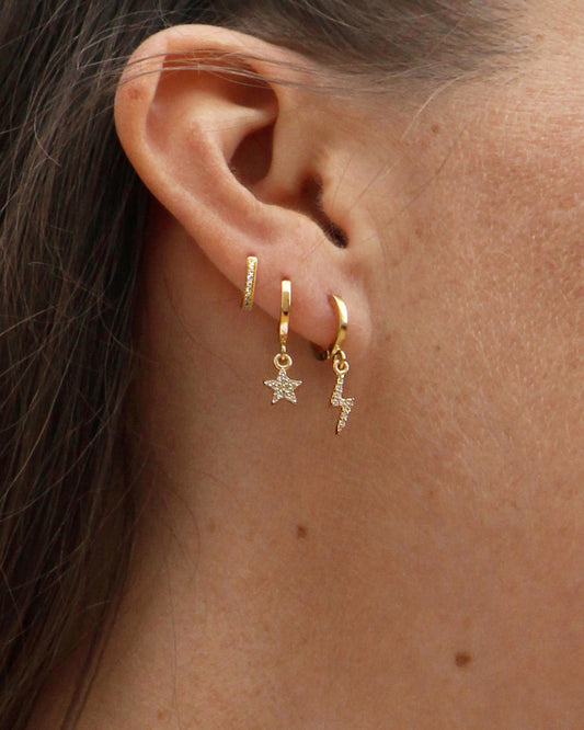 femme portant les boucles d'oreilles lily de chez nilai : elle porte l'anneau, l'étoile et l'éclair