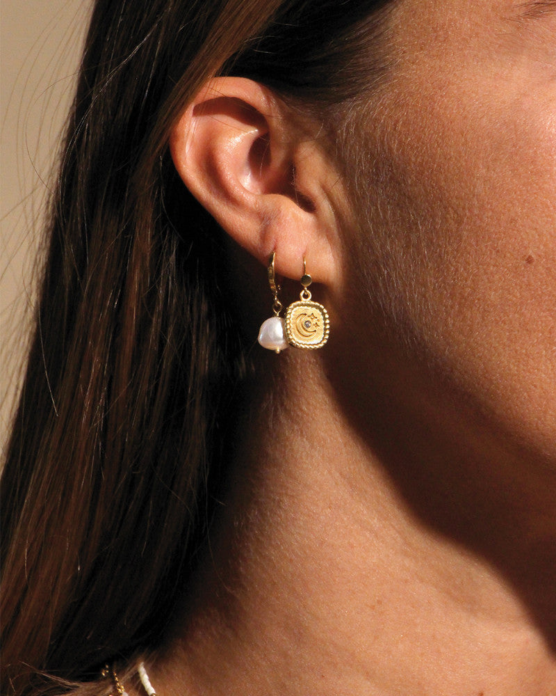 Femme portant des bijoux de la marque nilai : les boucles d'oreilles mini oracles et les créoles mini perla