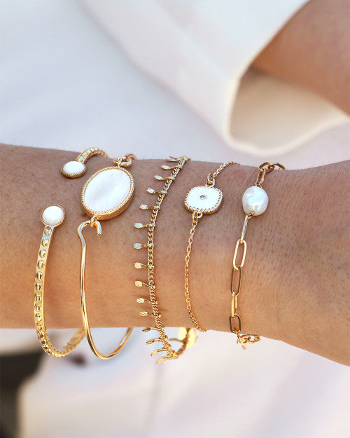 femme portant des bracelets blancs de chez nilai. elle porte l'alegria, le perla, le bracelet belize, le frida et l'athéna clouté