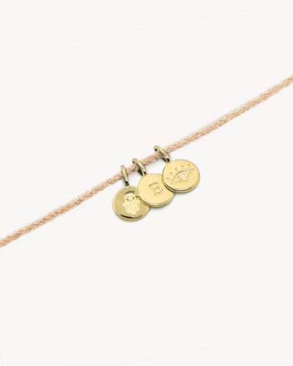 Bracelet corde beige nilai avec médailles gravées de la lettre E, un oeil et la main de fatma
