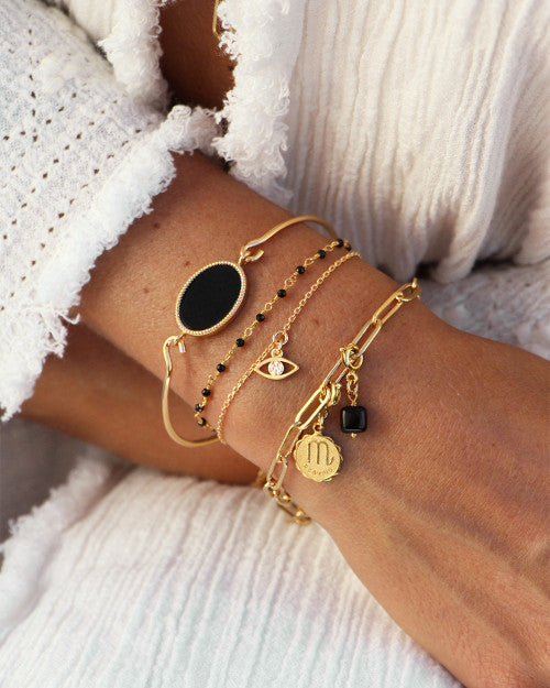 Femme portant des bracelets Nilaï : le mini stones noir, le lily oeil, le jonc frida et le bracelet pure