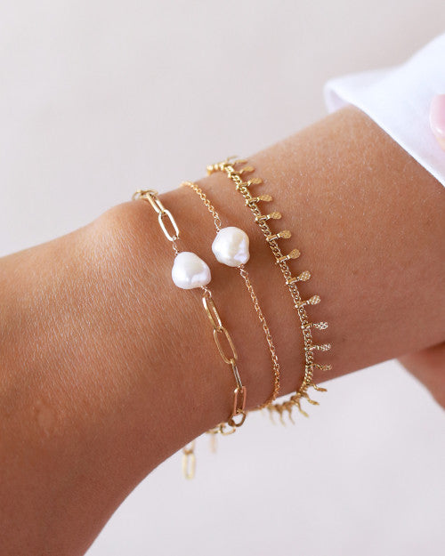 poignet portant bijoux perles blanches dorés