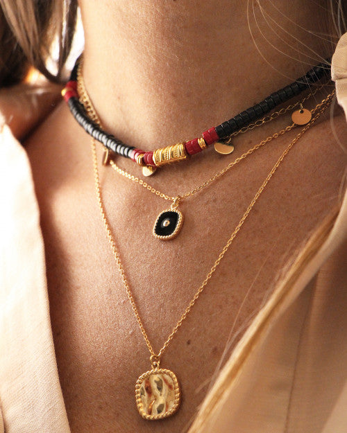 femme portant un collier surfeur, un collier à médaille carrée noire et un collier à médaille carrée dorée 