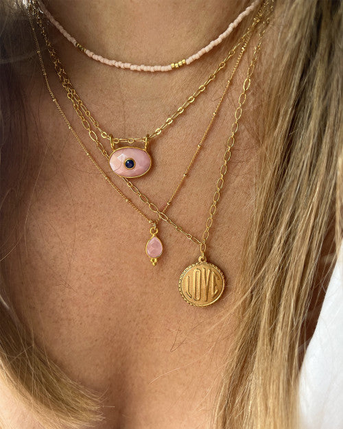 femme portant des bijoux roses de chez nilai : le collier love, le collier mini deva, le collier little india et le collier new delhi