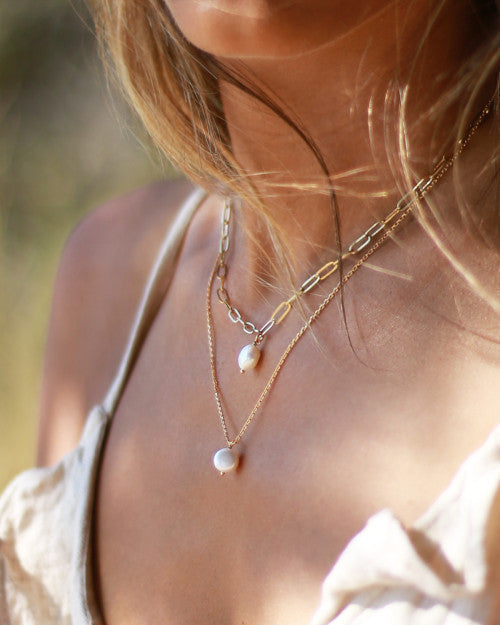 femme bronzée portant collier doré et orné perles blanches nila