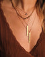 femme portant un pull marron ainsi que des bijoux de la marque nilai. elle porte le collier lily oeil, le collier double lock, et des colliers oracles