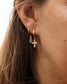 femme portant une mini créole avec croix et boucles d'oreilles avec pierre